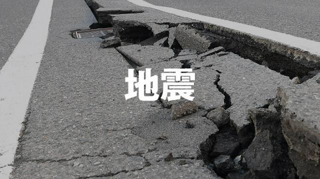 ひび割れた道路の写真の中央に「地震」の文字が入っている