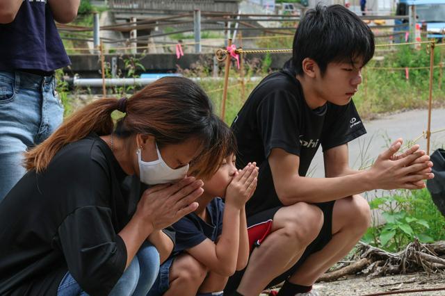 1年前の豪雨災害で、被害のあった場所で手をあわせる人たち