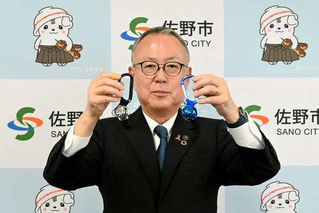 記者会見でクマよけの鈴を見せる栃木県佐野市の金子裕市長