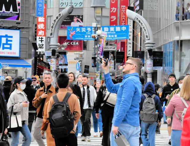 渋谷駅前のスクランブル交差点で記念撮影する外国人観光客ら