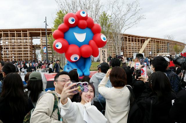 大阪・関西万博会場のミャクミャク像前で写真を撮る人たち