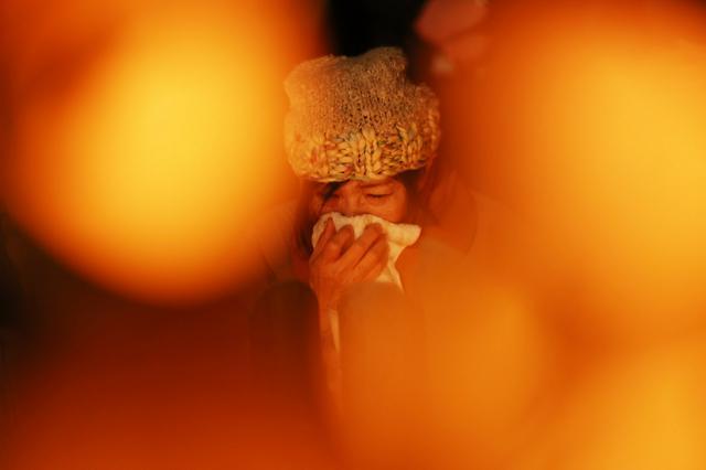 竹灯籠（とうろう）の前で涙を浮かべる女性