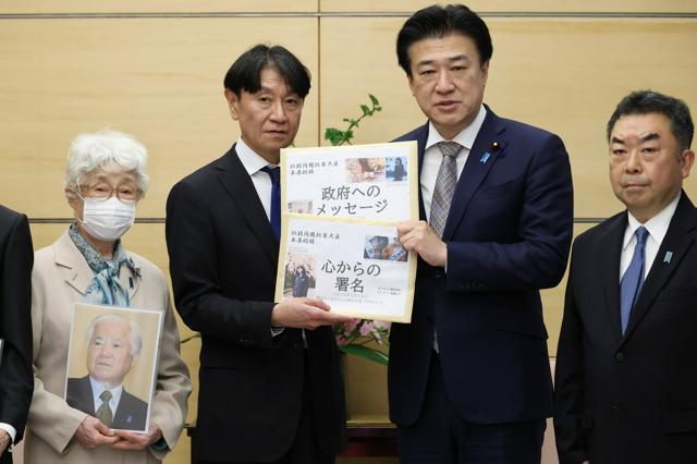 「横田めぐみさんとの再会を誓う同級生の会」の池田正樹代表（中央左）から署名簿などを受け取る拉致問題担当相の木原稔官房長官（同右）。左端は横田早紀江さん