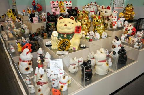 白や金色などいろいろなデザインの招き猫の貯金箱が集めて置かれている