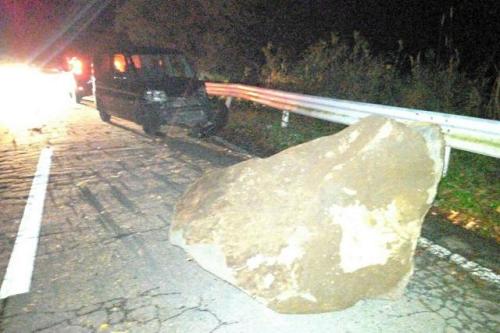 道路をふさいだ大きな石。道路脇の斜面から落ちたとみられ、奥の軽自動車は前部が壊れていた