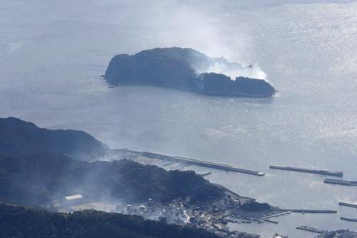 手前の住宅火災が飛び火したと思われ、煙を上げる蔦島（奥）