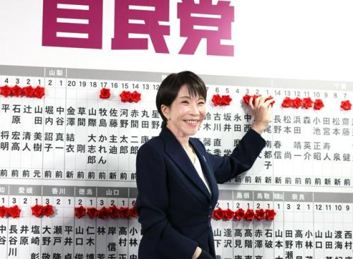 自民党の開票センターで、当選確実になった候補者名に笑顔で花をつける高市早苗首相